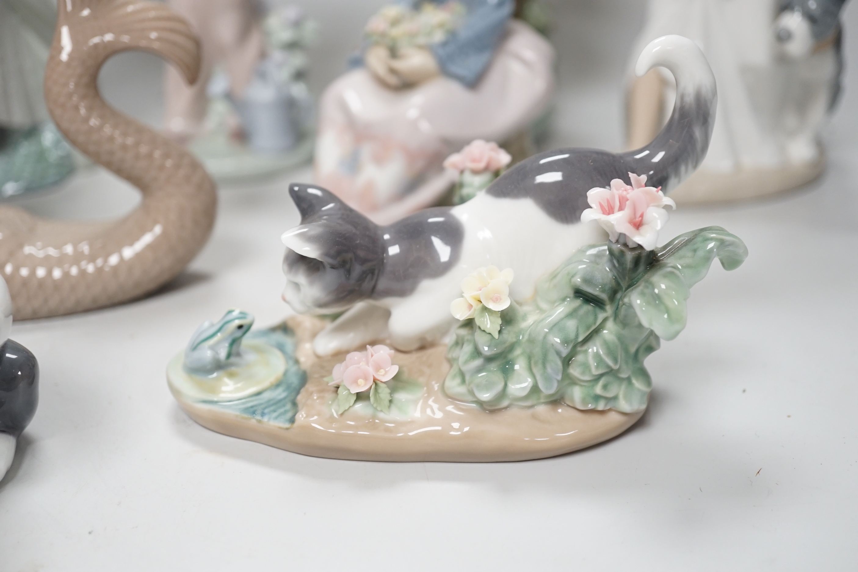 A large Lladro figure of a flower girl, mermaid, boy playing a drum and five other models including a Nao example, the largest 24cm high (8)